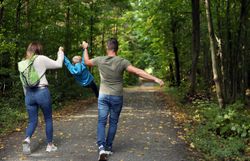 Eine Familie spaziert entlang eines Weges mitten durch den Wald. 