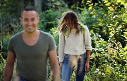 Ein Paar spaziert hintereinander im Wald im Naturpark Geras und kommt auf die Kamera zu. 