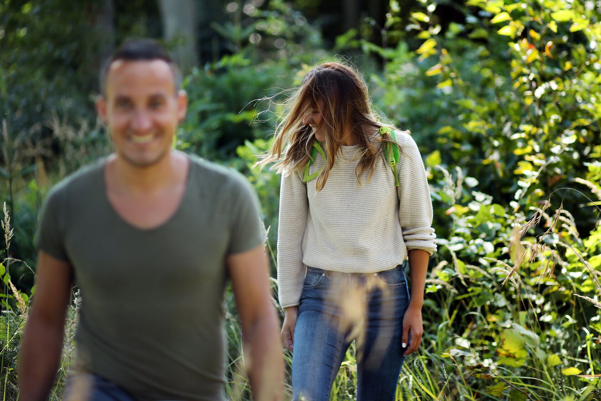 Ein Paar spaziert hintereinander im Wald im Naturpark Geras und kommt auf die Kamera zu. 